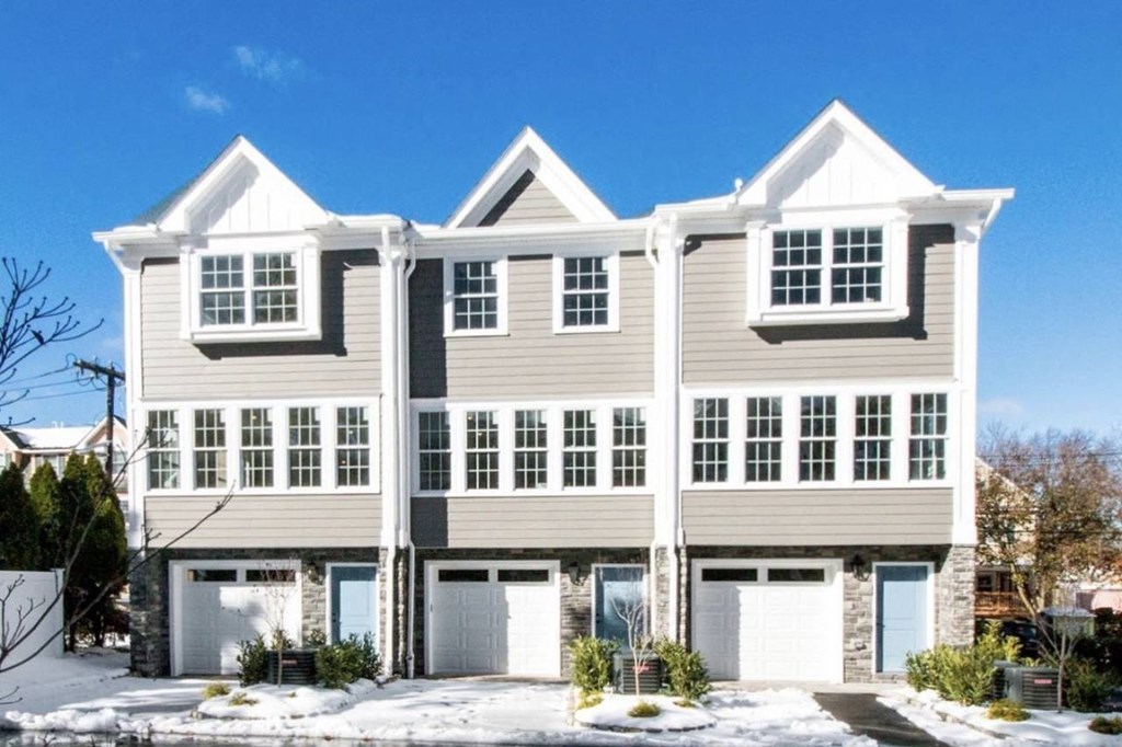 a large house with three garage doors in the snow