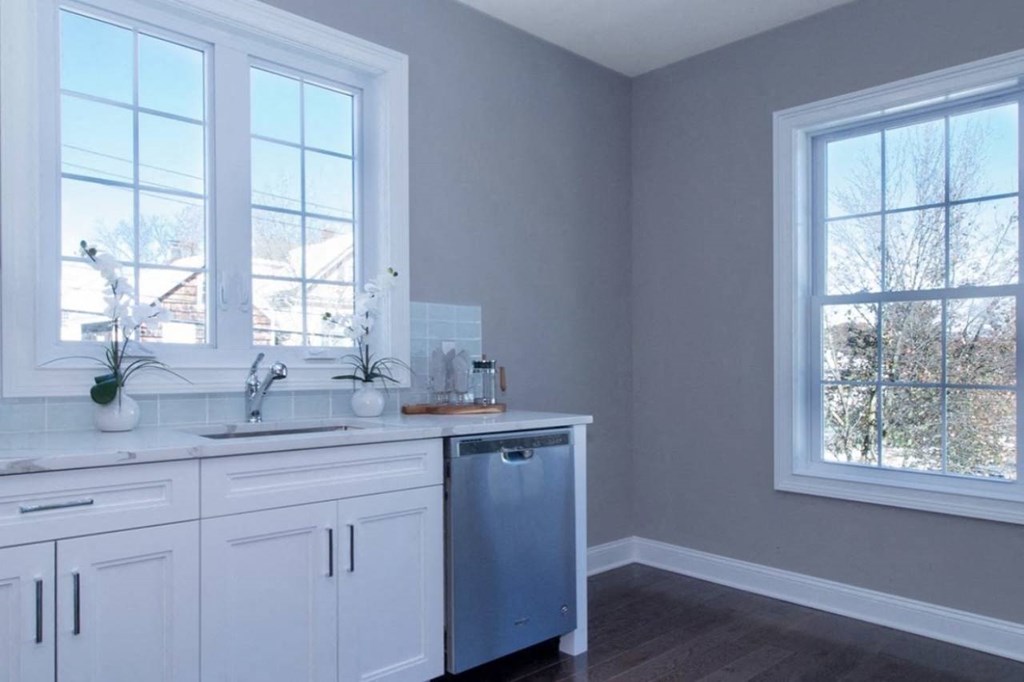 a kitchen with white cabinets and a sink and two windows