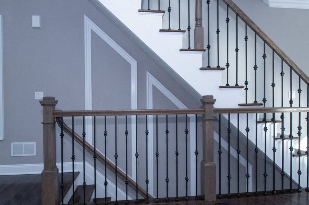 the bottom of a staircase with a wooden railing and a white wall