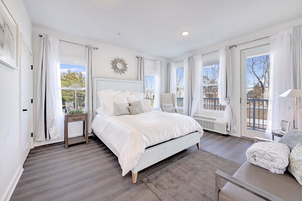 a white bedroom with a large bed and windows a white bedroom with a large bed and windows at The Franklin at Hillsborough Apartments, Hillsborough, New Jersey
