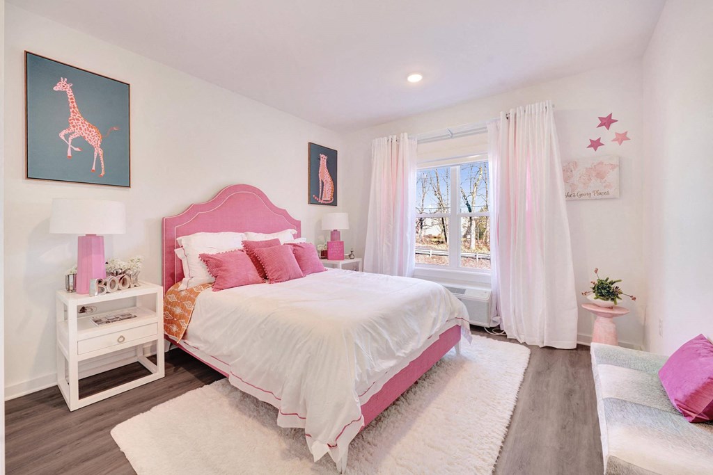 a pink and white bedroom with a bed and a window