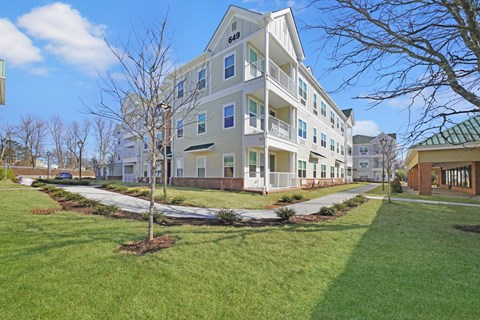 a large apartment building with a lawn and sidewalk in front of it at The Franklin at Hillsborough Apartments, Hillsborough, NJ 08844
