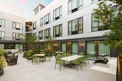 A courtyard with tables and chairs is surrounded by a building.