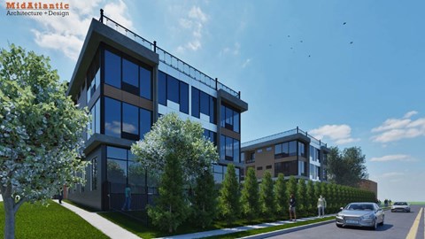A modern building with a glass facade is surrounded by trees and a clear blue sky.