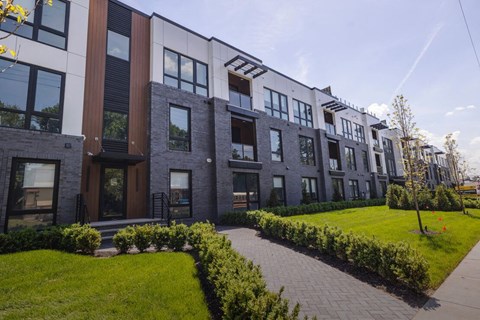 a row of modern apartment buildings with a sidewalk and grass