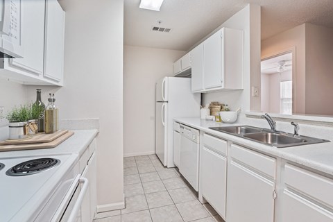 A white kitchen with a stove, sink, and refrigerator.