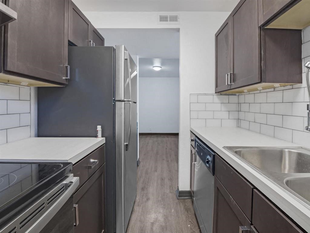 a kitchen with stainless steel appliances and wooden floors