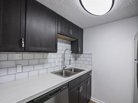 A kitchen with black cabinets and a white countertop.
