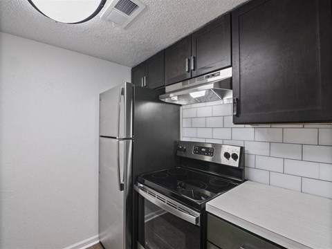 A kitchen with black cabinets and a stove top oven.