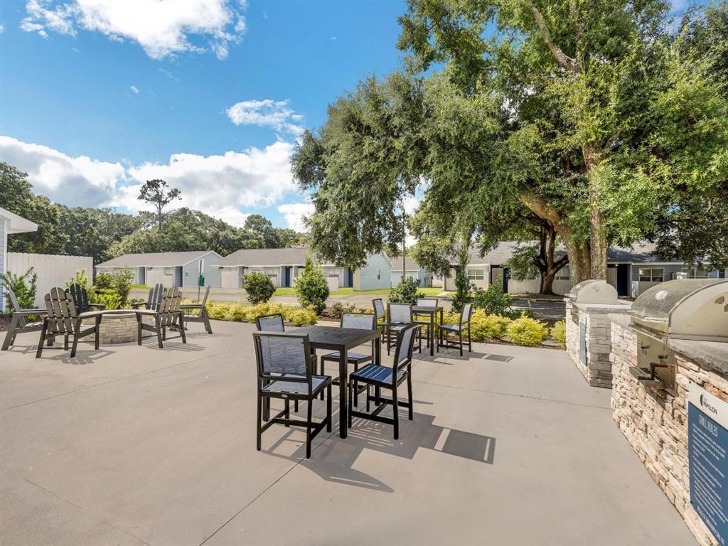 an outdoor patio with tables and chairs and trees at The Papillon, Pensacola Florida