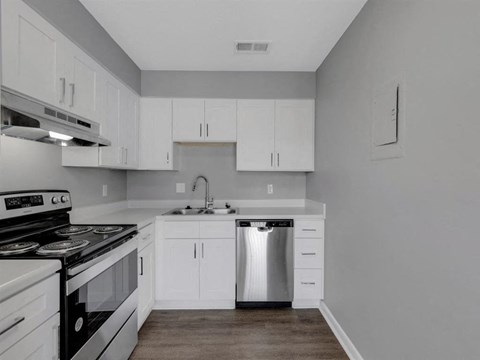 a white kitchen with stainless steel appliances and white cabinets