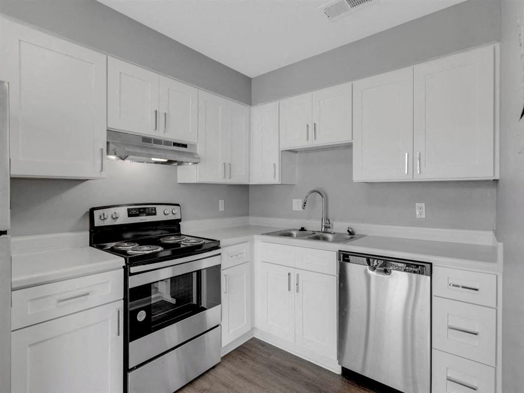 A kitchen with white cabinets and a stove top oven.