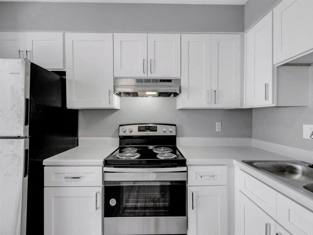 a white kitchen with a stove and a refrigerator