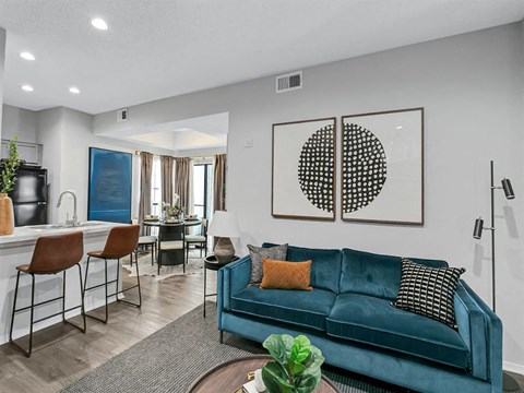 A living room with a blue couch and a painting on the wall.