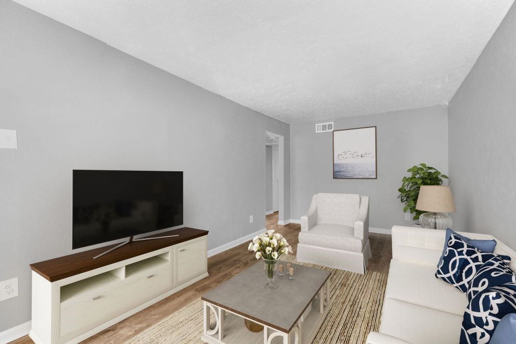 A living room with a white couch, a coffee table, and a flat screen TV.
