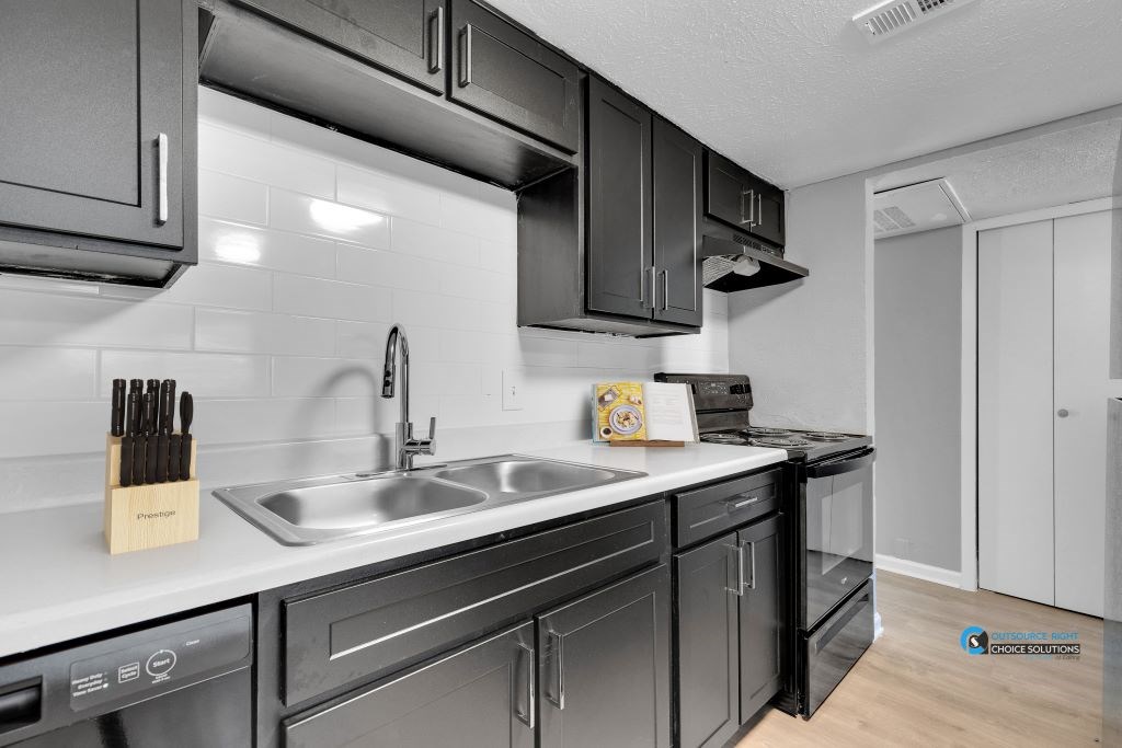 A modern kitchen with black cabinets and stainless steel appliances.