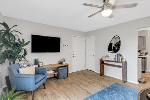 A living room with a blue chair and a flat screen TV mounted on the wall.