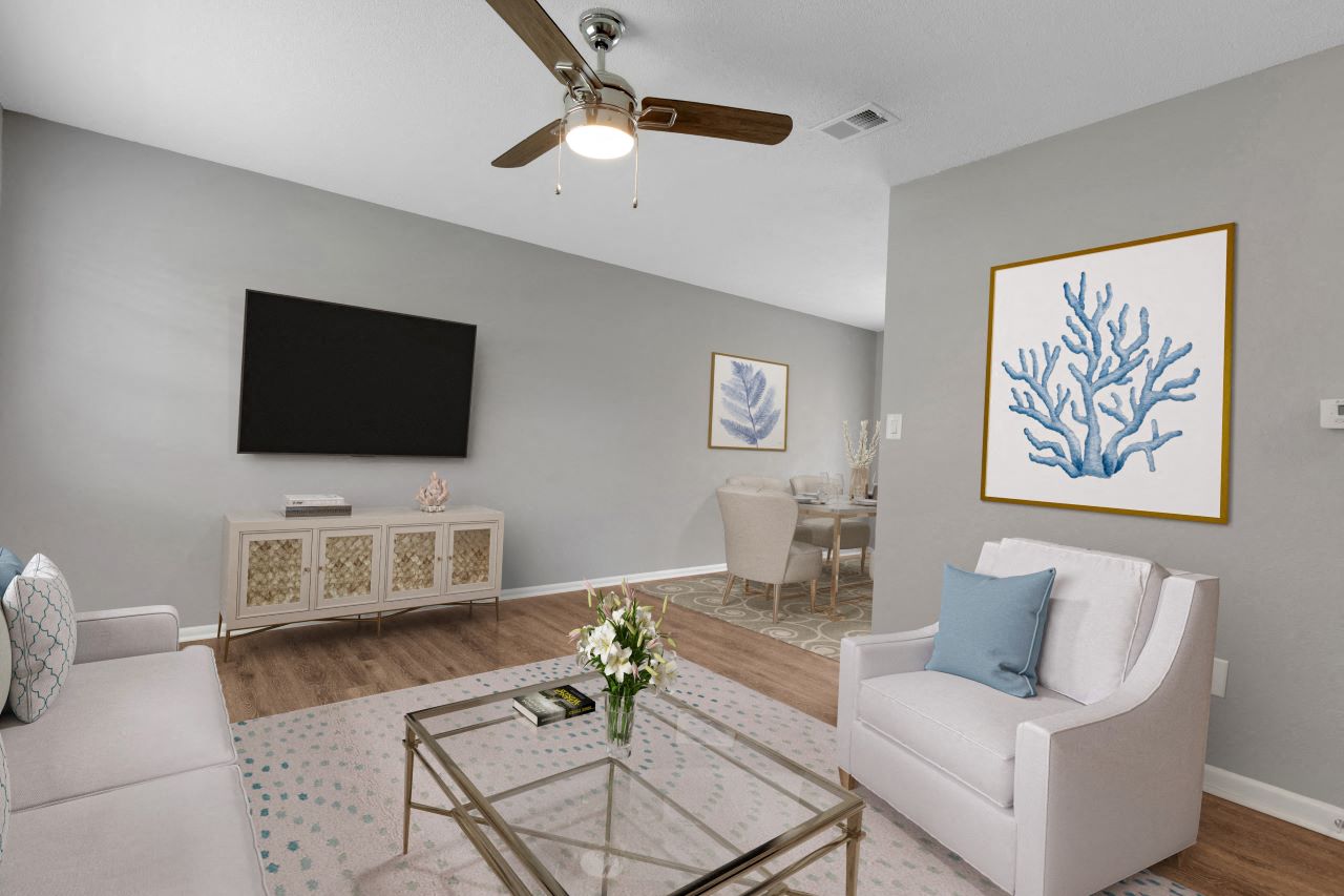 A living room with a white couch, a glass coffee table, and a painting on the wall.