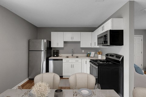a kitchen with white cabinets and black appliances and a dining table