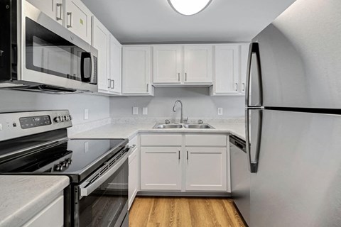 A modern kitchen with white cabinets and stainless steel appliances.