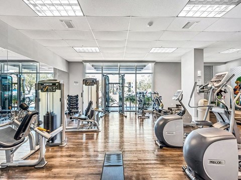 a gym with cardio machines and a wood floor