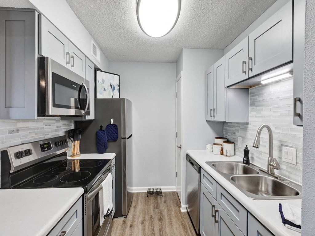 a kitchen with white cabinets and stainless steel appliances at The Emory, Pensacola, Florida