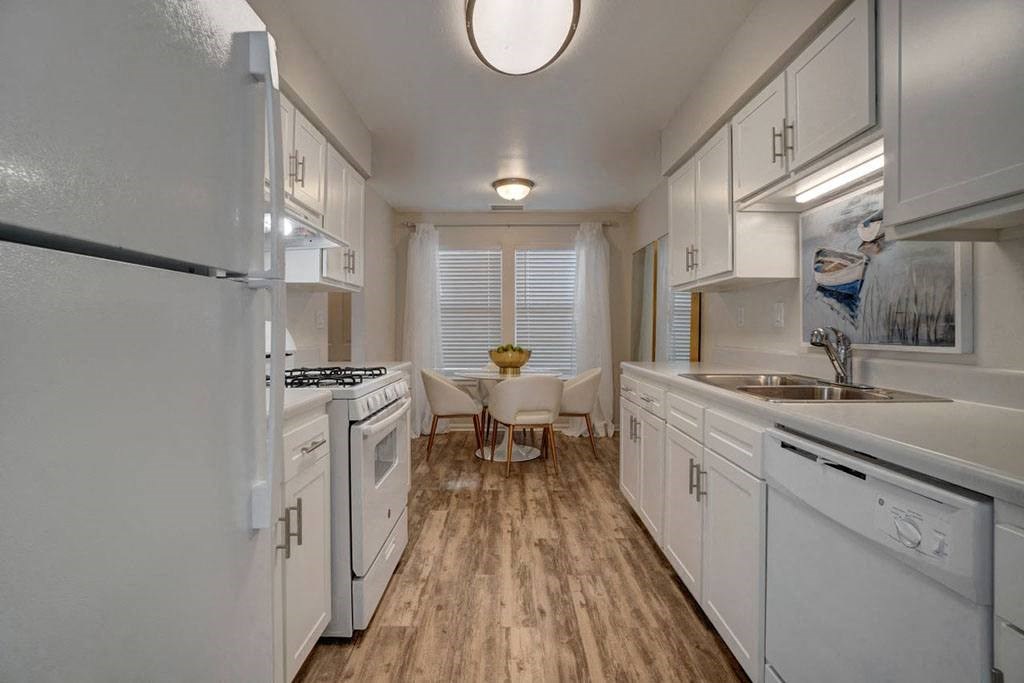 a large white kitchen with white cabinets and a wood floor a large white kitchen with white cabinets and a wood floor at Estates at Palm Bay, Fort Walton Beach, 32547