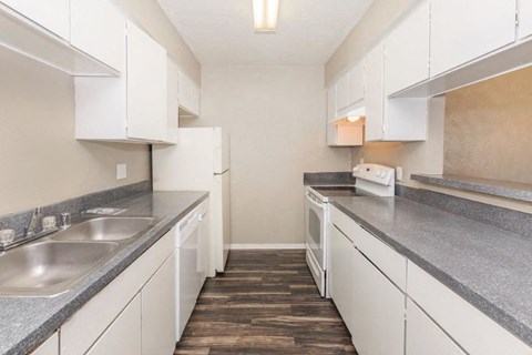 A kitchen with white cabinets and a wooden floor.
