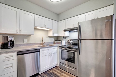 a kitchen with stainless steel appliances and white cabinets at Latitude 2976, Houston, 77042