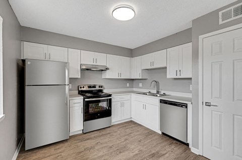 a white kitchen with stainless steel appliances and white cabinets