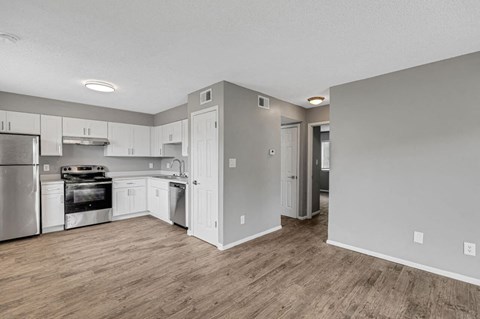 an empty kitchen with white cabinets and a wood floor