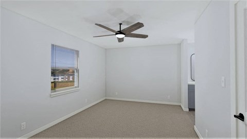 an empty room with a ceiling fan and a window