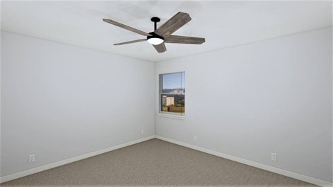 an empty room with a ceiling fan and a window