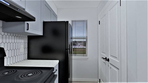 a kitchen with white cabinets and a black refrigerator