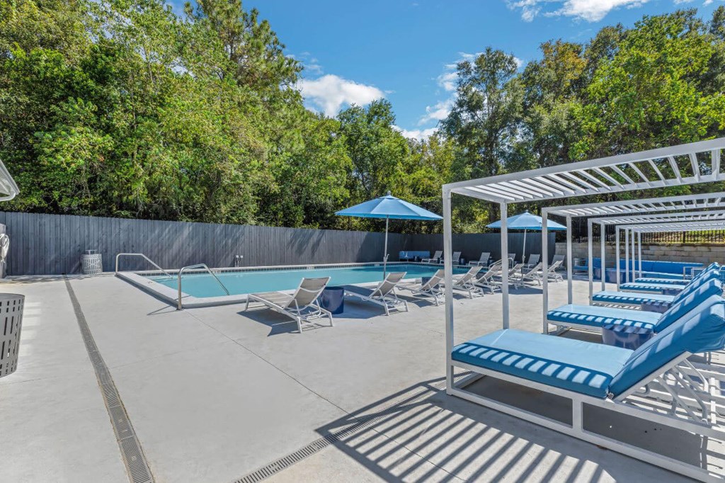 a pool with lounge chairs and umbrellas at The Lorient Apartments, Pensacola