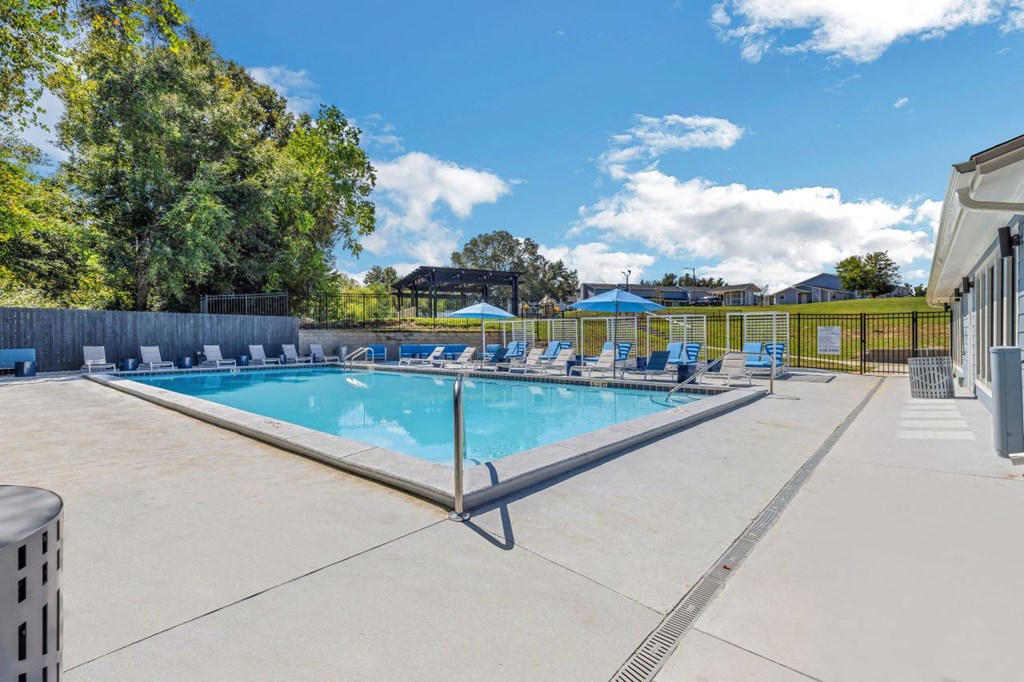 a resort style swimming pool with blue chairs around it at The Lorient Apartments, Pensacola, FL