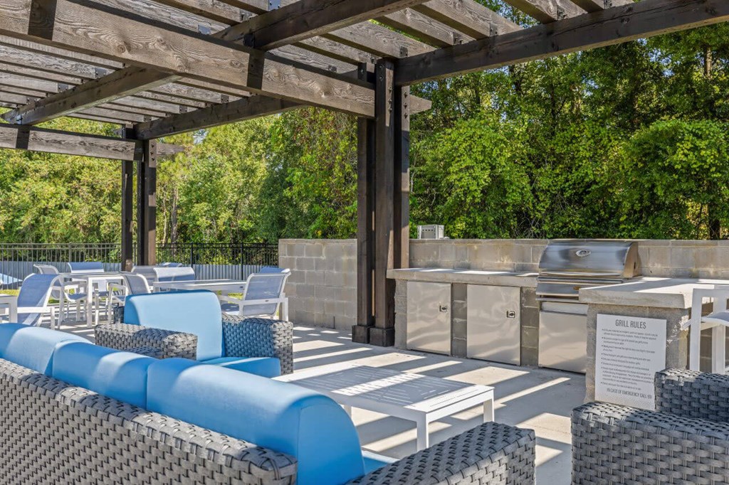 a swimming pool with a wall of plants and a blue water feature at The Lorient Apartments, Florida, 32514