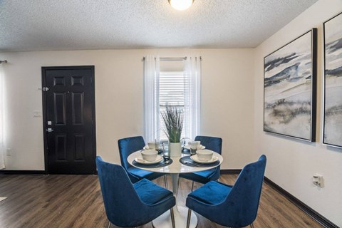 a dining room with a glass table and blue chairs at The Lorient Apartments, Pensacola, 32514