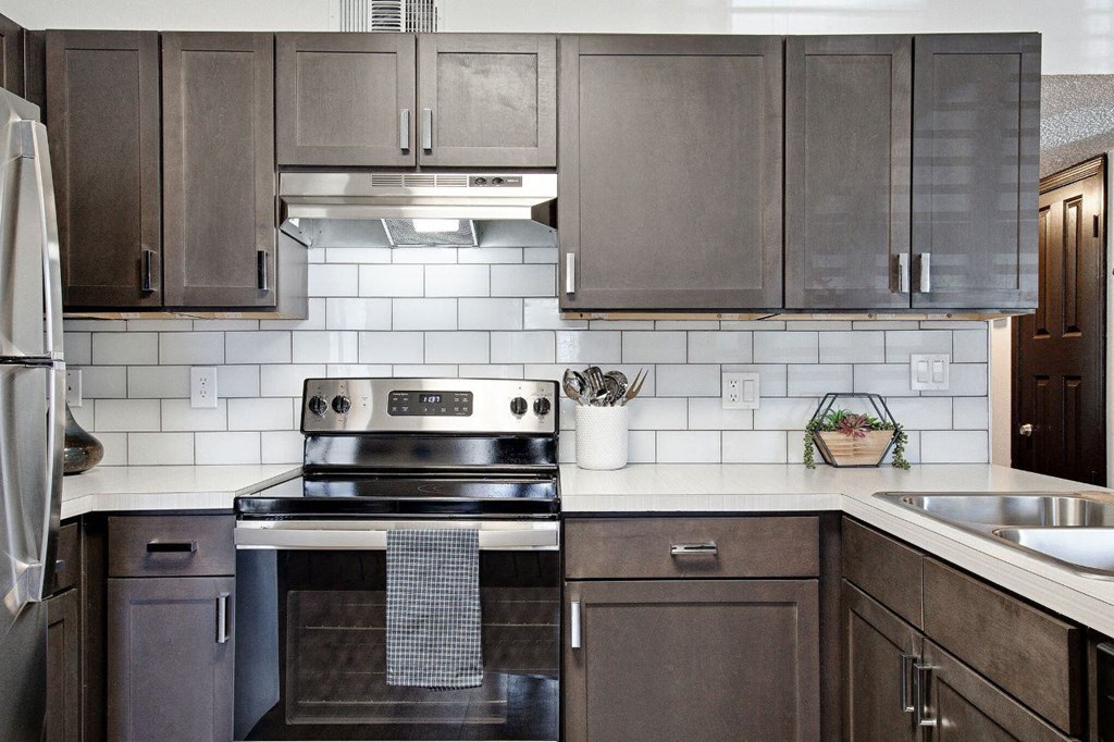 a kitchen with stainless steel appliances and wooden cabinets at The Lorient Apartments, Pensacola, FL, 32514