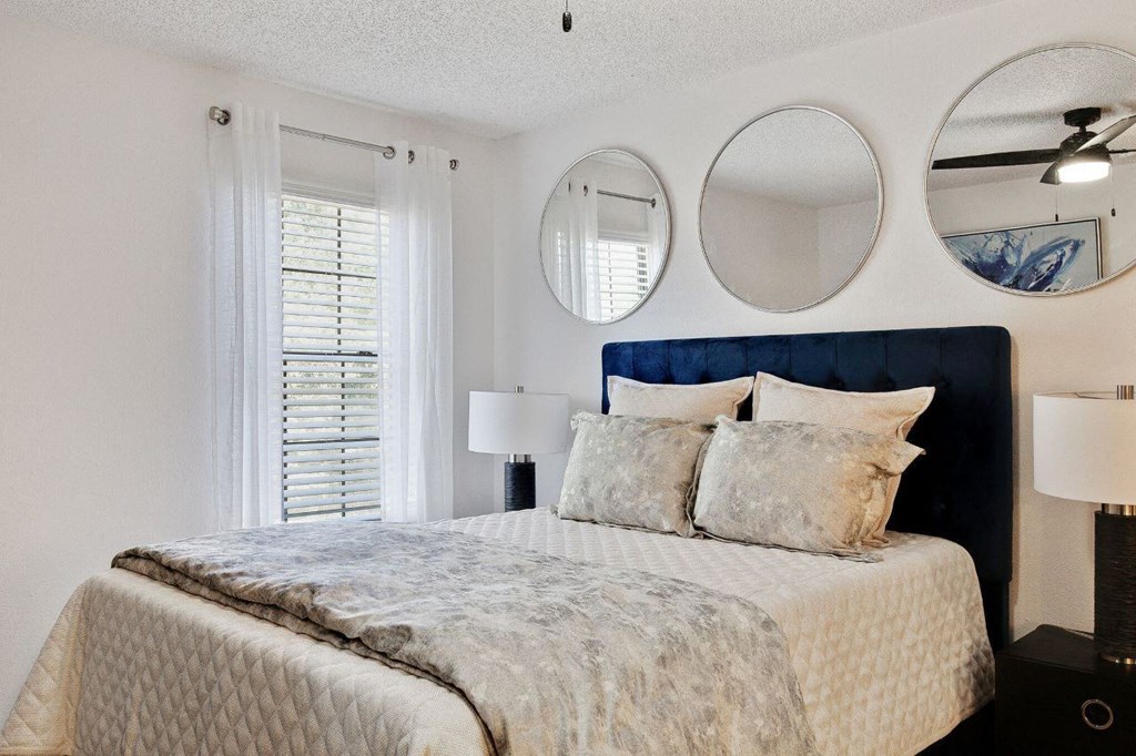 a bedroom with a bed and two mirrors above it at The Lorient Apartments, Florida