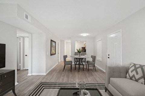 a living room and dining room with white walls and wood floors
