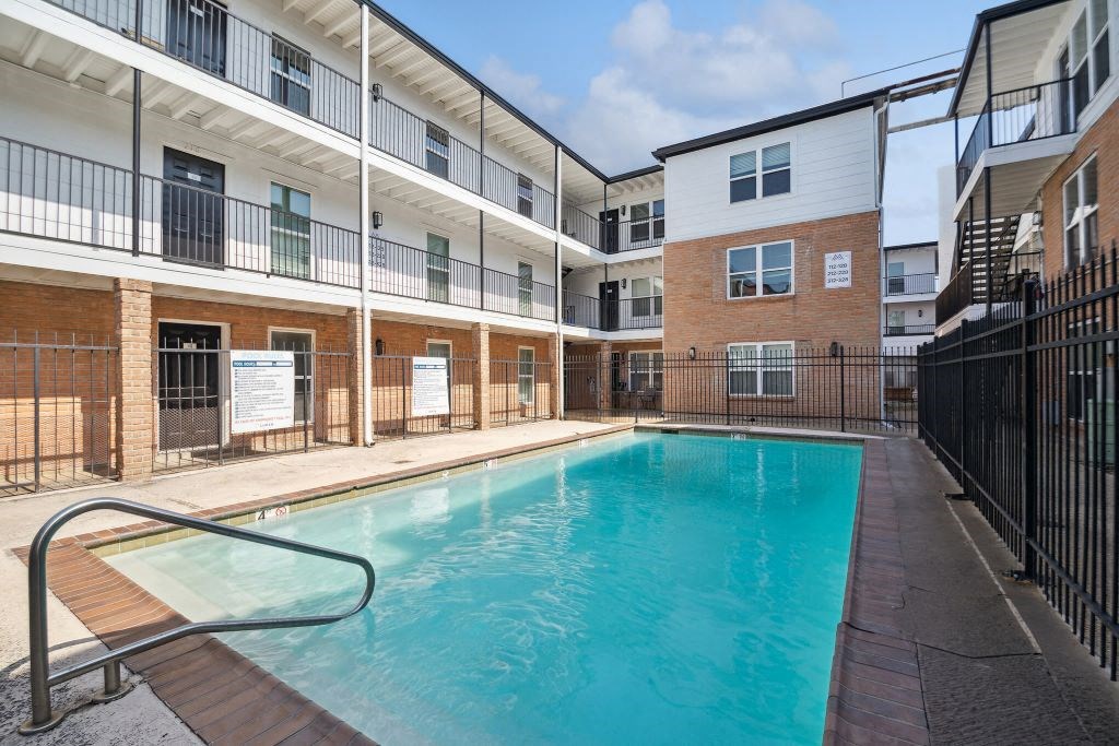 the pool is in front of an apartment building with a pool