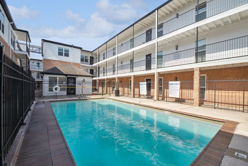 the pool is next to a building with a fence around it