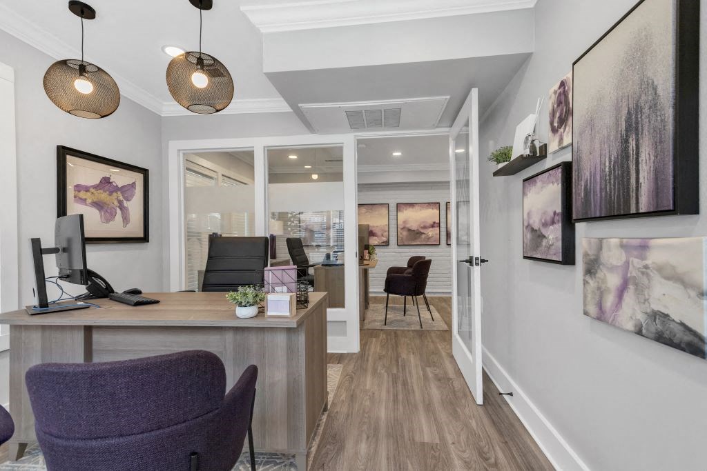 a home office with a desk and a hallway to a living room