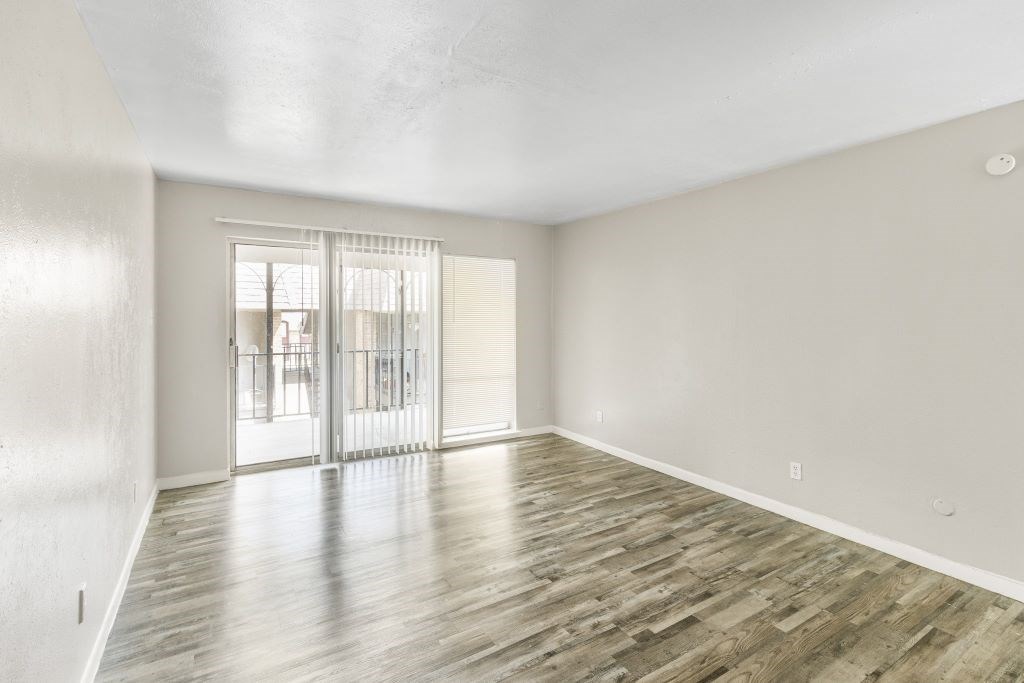 A room with wooden flooring and a sliding glass door.