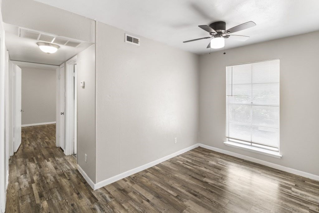 A room with a ceiling fan and a window with blinds.