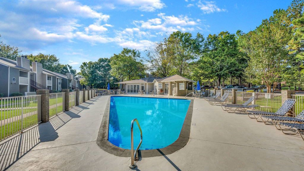 A swimming pool surrounded by a fence and trees.