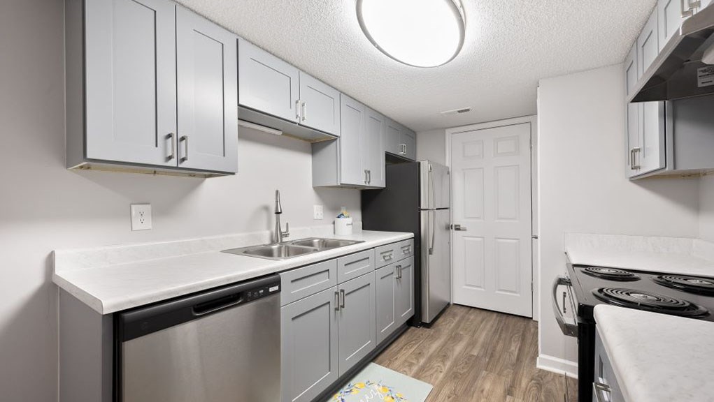 A kitchen with a white counter top and stainless steel appliances.