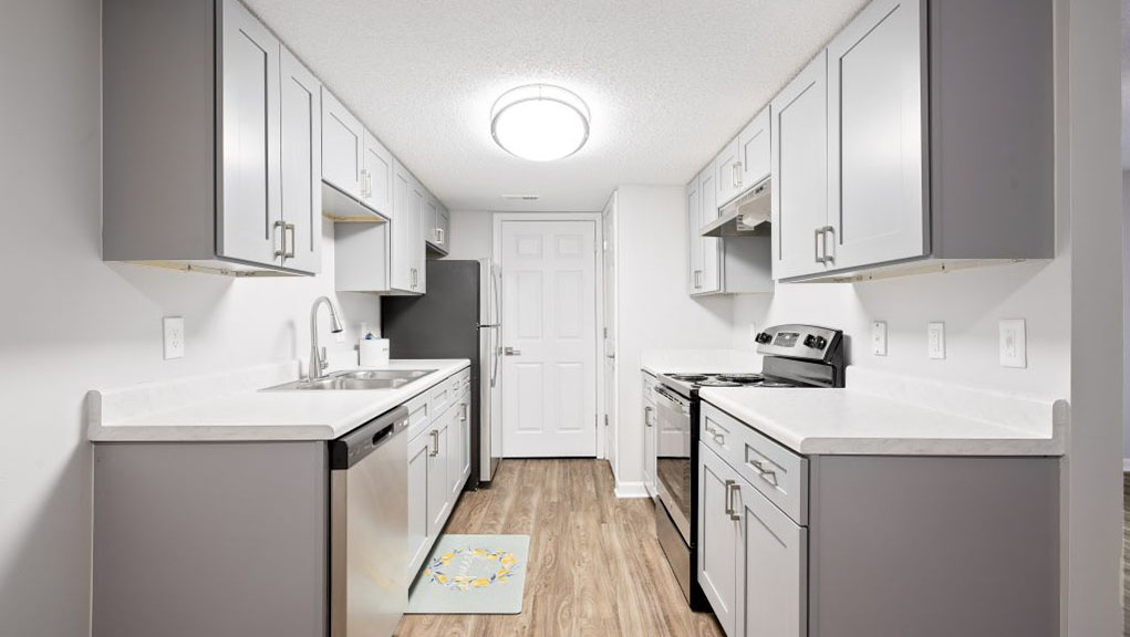 A kitchen with white cabinets and a white sink.