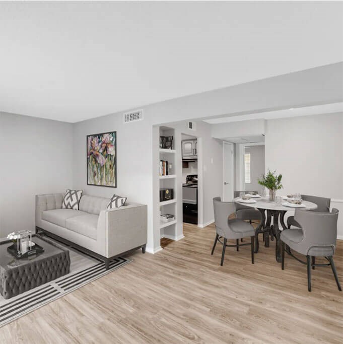A living room with a white couch and a dining table with grey chairs.